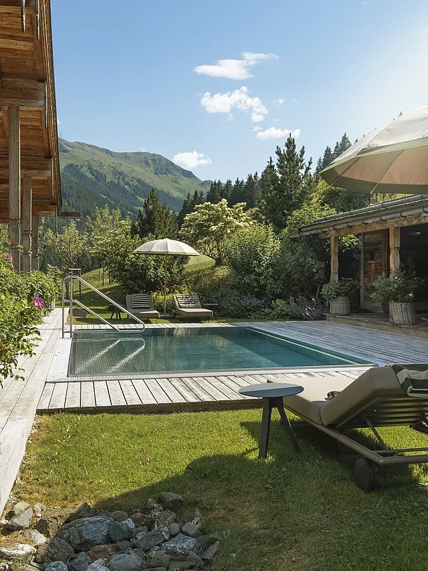liegen und outdoor-pool mit aussicht auf die berge im luxuschalet die schmiedalm in österreich