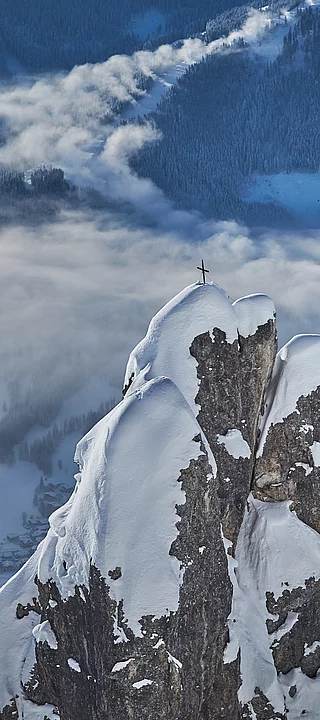 A summit cross on a snow-covered mountain in Saalbach Hinterglemm