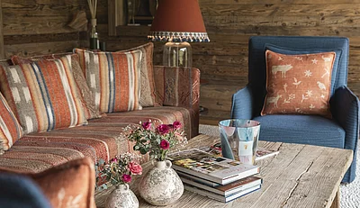 Detailaufnahmen Tisch mit Blumen und Couchsessel im Wintergarten Ruheraum im Chalet Die Schmiedalm in Saalbach Hinterglemm.