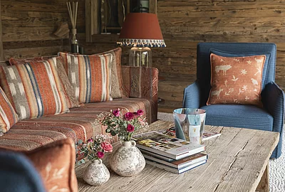 Detailaufnahmen Tisch mit Blumen und Couchsessel im Wintergarten Ruheraum im Chalet Die Schmiedalm in Saalbach Hinterglemm.