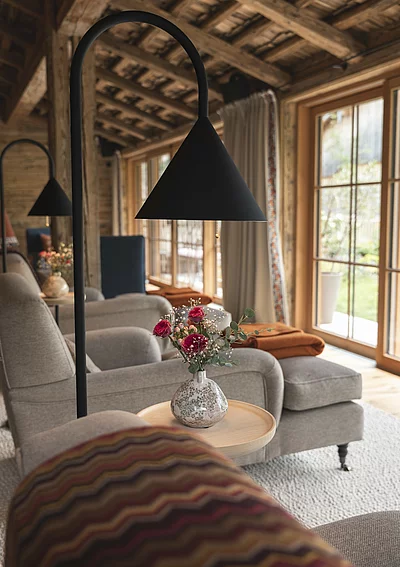 Detailaufnahmen Tisch mit Blumen und Couchsessel im Wintergarten Ruheraum im Chalet Die Schmiedalm in Saalbach Hinterglemm.