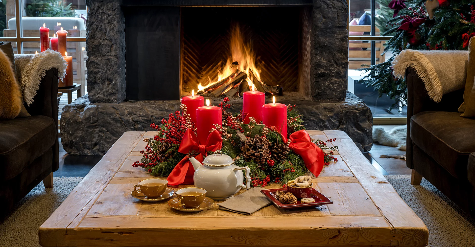 Weihnachtliche Deko auf einem Holztisch vor einem Kamin in der Schmiedalm - dem Chalet in Saalbach Hinterglemm