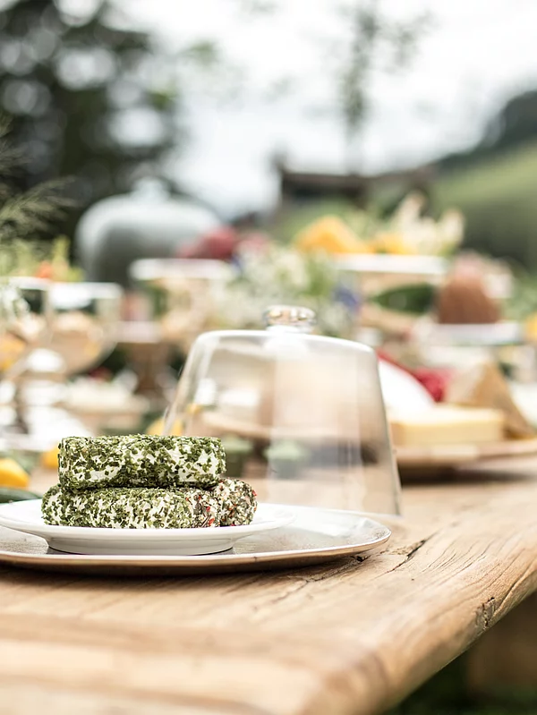 Herb cream cheese with spices on a plate under a glass cover on the wooden table at the Schmiedalm.