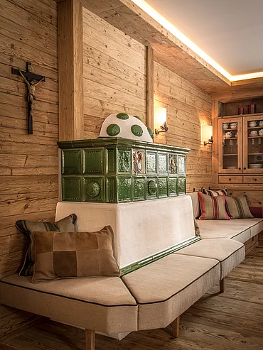 A large tiled stove with cosy seating area in the Schmiedalm - the chalet