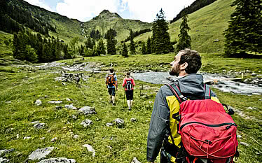 Gruppe beim Wandern endlang eines Baches im Sommerurlaub in Saalbach Hinterglemm