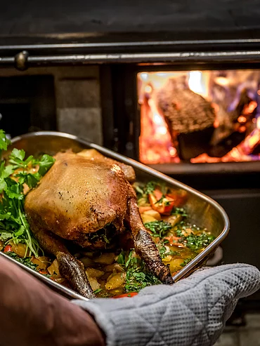 Ein köstlich gefüllter Braten wird auf der Schmiedalm aus dem Holzofen genommen