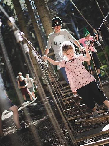 Family holiday deluxe Two children cross a suspension bridge on the Baumwifpelweg in Saalbach Hinterglemm