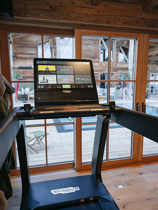 Fittnessbereich im Chalet die Schmiedalm mit Cardio Geräten und Aussicht auf den Pool